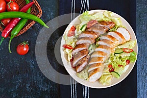 Juicy home made sausage with a light spring salad of fresh vegetables on a black wooden background. A traditional Easter dish.