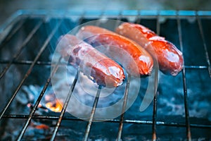 Juicy hot dog sausages cooking on fire