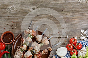 Juicy kebabs of pork and fresh vegetables. Still life on a wooden background. Place under your text.