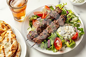 Juicy lamb kebabs with fresh Greek salad and tzatziki on a white plate