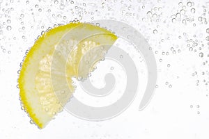 Juicy lemon slice in soda water against white background, closeup. Space for text