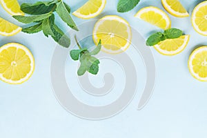 Juicy lemon slices and mint leaves on blue table top view. Flat lay style.