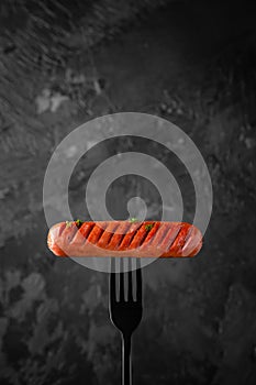 Juicy meat sausage grilled on a fork in the smoke. Tasty food.