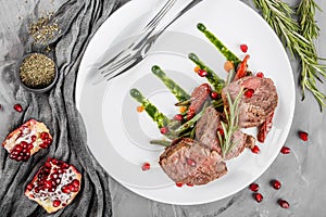 Juicy medium beef fillet steaks mignon with green beans, pomegranate and sauce in plate on grey background. Hot Meat Dishes, top