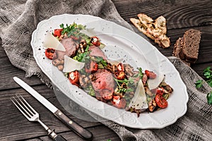 Juicy medium beef fillet steaks mignon with grilled vegetables, mushrooms, tomatoes, cheese in plate on rustic wooden background