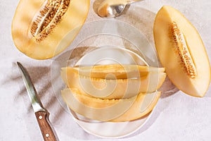 Juicy melon slices on a plate with a knife on a white plate with beautiful shadows