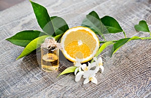 Juicy Orange cut in two parts and neroli, flowers of orange tree, on rustic wood background.