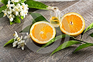 Juicy Orange cut in two parts and neroli, flowers of orange tree, on rustic wood background.