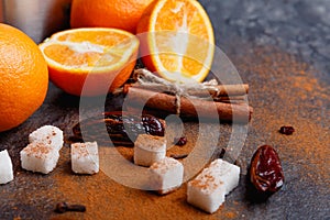 Juicy orange, dates, sugar and cinnamon sticks on the kitchen table. Indoors.