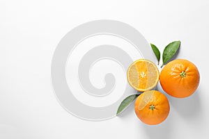 Juicy oranges and leaves on white, top view