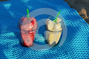 Pieces of fruit in glasses on a blue blanket on the sandy beach. watermelon and melon at sunset. background for the design.