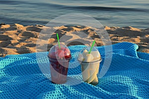 Pieces of fruit in glasses on a blue blanket on the sandy beach. watermelon and melon at sunset. background for the design.