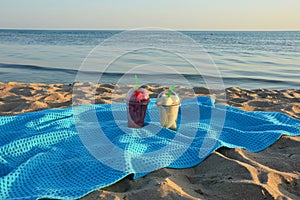 Pieces of fruit in glasses on a blue blanket on the sandy beach. watermelon and melon at sunset. background for the design.