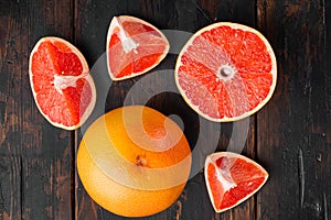 Juicy pink grapefruit cut , on old dark  wooden table background, top view flat lay