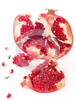 Juicy pomegranate and its half with leaves. Isolated on a white background.