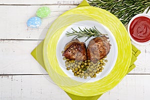 Juicy pork medallions wrapped in bacon, serve with green peas and a sprig of rosemary