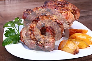 Juicy pork neck chops are grilled with potatoes on a white plate.