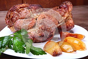 Juicy pork neck chops are grilled with potatoes on a white plate.