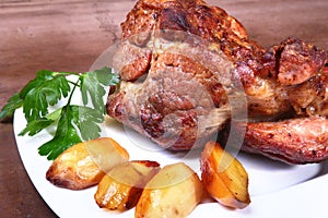 Juicy pork neck chops are grilled with potatoes on a white plate.