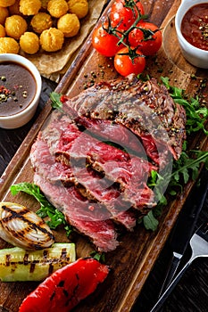 Juicy rare sliced grilled fillet steak served with tomatoes and