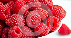 juicy raspberries stacked in a white bowl