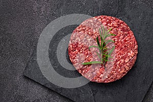 Juicy raw burger patty against a dark backdrop