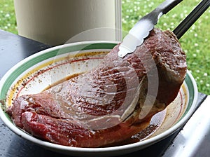 Juicy raw London Broil in bowl with thongs