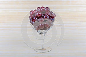 Juicy red fresh cherry in a glass transparent glass.Beautiful bowl with berries on a light natural wooden background.Healthy vitam
