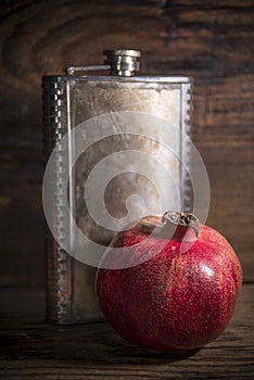 Juicy red pomegranates with iron flask on wooden background
