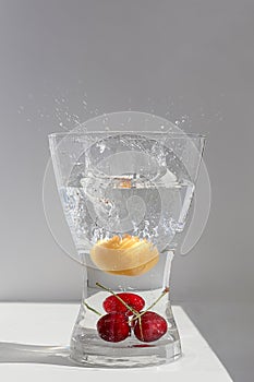 Juicy ripe fruit red cherries floating in a glass vessel in clear transparent water with air bubbles