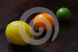 Juicy ripe lemon, citrus meyeri and lime on wooden background. Citrus fruit on a dark table. Beautiful fresh fruit. Food