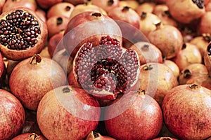 Juicy ripe Pomegranate fruit, Punica granatum. Whole and cut open fruits on display market counter