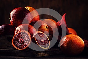 Juicy ripe shiny red bloody oranges in tray for making refreshing cocktail on rustic wooden table background, still life,