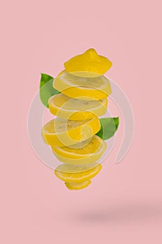 Juicy ripe sliced lemons falling in the air  isolated on light pink background. Creative food concept