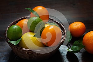 Juicy ripe slices of orange, lemon, grapefruit and lime on a dark background. Sliced citrus in a basket on a brown wooden table.