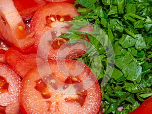 Juicy ripe tomato cut into slices. Finely chopped parsley. Snack on the table. Harvest from the garden