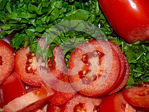 Juicy ripe tomato cut into slices. Finely chopped parsley. Snack on the table. Harvest from the garden