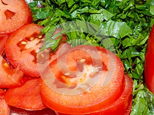 Juicy ripe tomato cut into slices. Finely chopped parsley. Snack on the table. Harvest from the garden