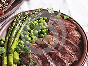 Juicy roasted beef chopped steak, with green peas, asparagus, on plate close up