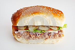 Juicy sandwich with cucumbers, lettuce, cheese, onion and tuna on a white background