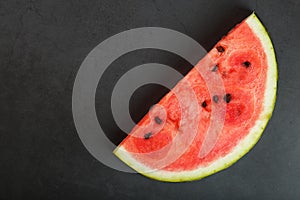 Juicy slice of red watermelon on a stone black background. Conceptual colors of summer. Top view as a background