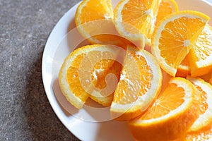 Juicy sliced orange on white round plate.