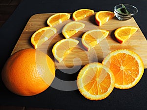 Juicy slices of sliced orange on a cutting board next to a whole orange