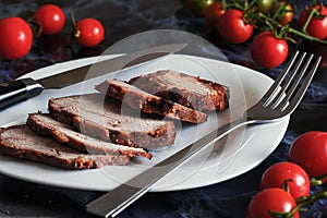 Juicy steak well done roast pork with red sauce and Basil leaves on a white plate over a black marble table