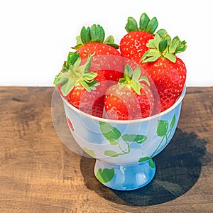 Juicy strawberries fill a dainty cup, ripe and enticing