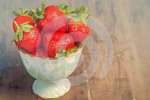 Juicy strawberries fill a dainty cup, ripe and enticing