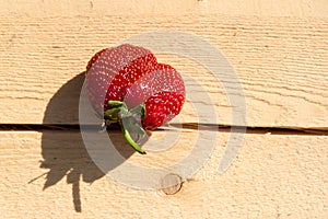 Juicy strawberry on a rough fresh board with a crack. Rustic style. Close-up, copy space