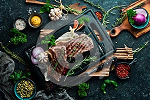 Juicy striploin steak grilled with spices and rosemary. On a black concrete background.