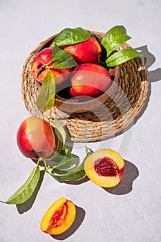 Juicy and sweet nectarines in a bowl on a light background with shadow. Healthy farm fruit concept