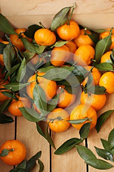 Juicy tangerines with green leaves in a wooden box